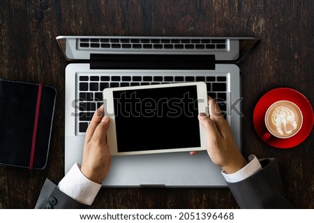 Woman hands typing laptop with office stuff with Movie clapper, laptop, smartphone, tablet, coffee cup, pen, notepad and documents on the table top view shot.
