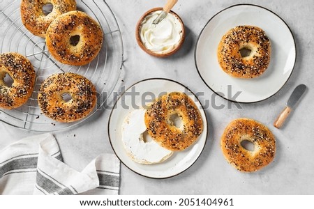 Fresh baked sourdough New York style bagels with cream cheese on light gray table, top view Royalty-Free Stock Photo #2051404961