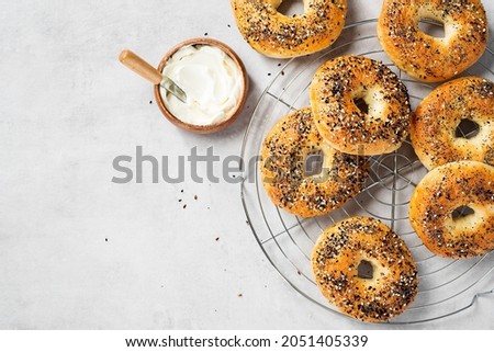 Fresh baked sourdough New York style bagels with cream cheese on light gray table, top view Royalty-Free Stock Photo #2051405339