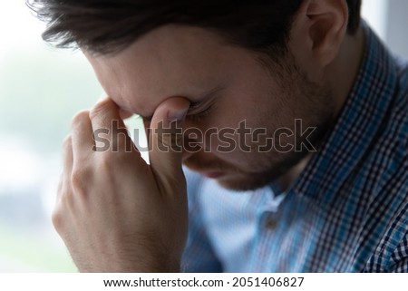 Crop close up of frustrated young man touching forehead, suffering from strong headache, migraine, upset exhausted guy feeling depressed and tired, relieving pain, thinking about personal problems Royalty-Free Stock Photo #2051406827