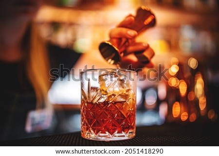 woman bartender hand making negroni cocktail. Negroni classic cocktail and gin short drink with sweet vermouth, red bitter liqueur Royalty-Free Stock Photo #2051418290