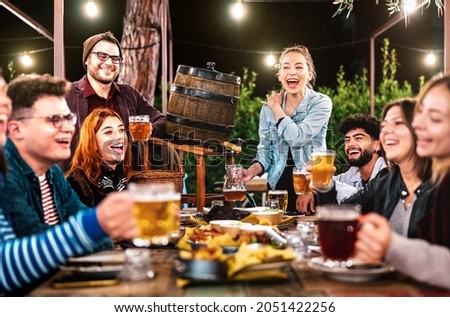 Happy men and women having fun drinking out at beer garden - Social gathering life style concept on young people enjoying weekend hangout time together at night - Warm dark filter Royalty-Free Stock Photo #2051422256