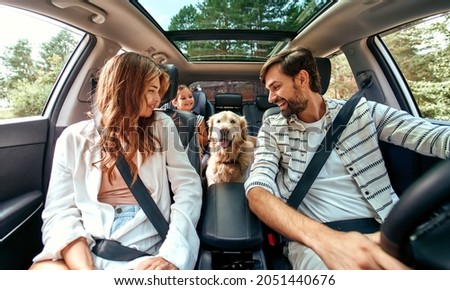 The whole family is driving for the weekend. Mom and Dad with their daughter and a Labrador dog are sitting in the car. Leisure, travel, tourism. Royalty-Free Stock Photo #2051440676