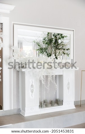 Wedding decor on a white fireplace. Compositions of white flowers and candles.