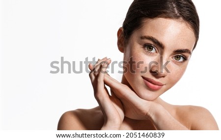 Beauty face and spa. Woman with freckles, clean nourished skin, biting lip and look aside. Girl model using antiaging cosmetics and vitamin c serum for bettet smoother skin tone, white background Royalty-Free Stock Photo #2051460839