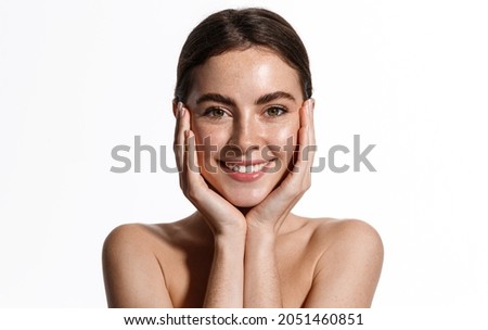 Skin care. Woman with beauty face touching healthy facial skin portrait. Beautiful smiling girl model with natural makeup touching glowing hydrated skin on white background closeup