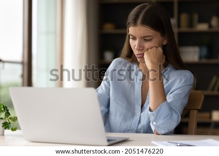 Tired bored millennial student girl watching dull learning webinar, online lesson, having problems with slow app, software on laptop. Lazy office worker, employee working on computer, feeling apathy Royalty-Free Stock Photo #2051476220