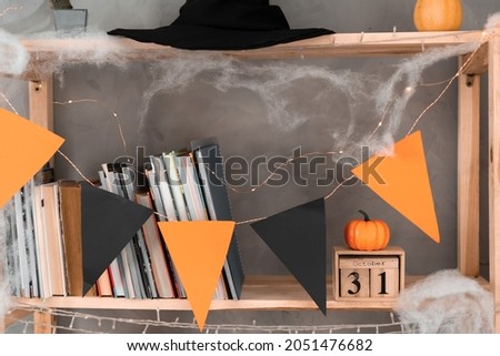 Happy Halloween date October 31 on wooden calendar. bookshelf decoration with orange black flags. Autumn holiday concept. Copy space