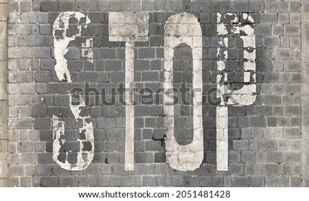 Stop Sign Painted on Stone Tile floor, worn-age. Cobblestone pavement close-up. 