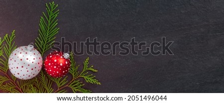 White and red Christmas toy balls, holiday confetti and New Year tree branches on black background. 

Festive banner, winter decoration. Minimal celebration concept with copy space.