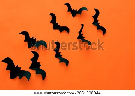 Halloween concept, black paper bats on an orange background. High quality photo
