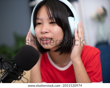 Little Asian girl singing a song in home recording studio.