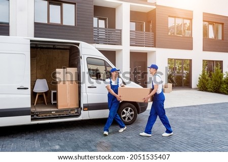 Two removal company workers are loading boxes into a minibus. Royalty-Free Stock Photo #2051535407