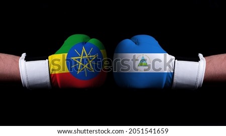 Two hands of wearing boxing gloves with Nicaragua and Ethiopia flag. Boxing competition concept. Confrontation between two countries