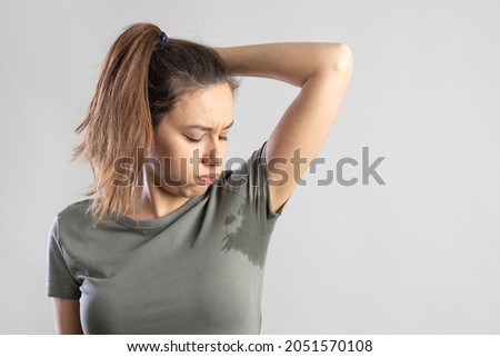 Excessive sweating problems. Young woman with her arm raised with her armpits sweat.
 Royalty-Free Stock Photo #2051570108