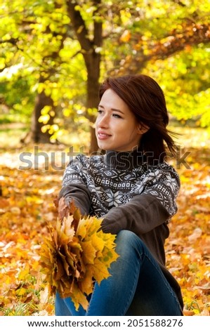 Сute girl in jeans and sweater in autumn foliage