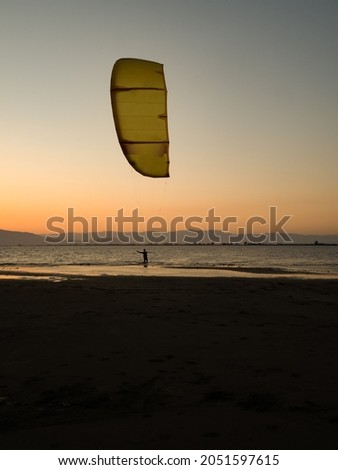 Unrecognizable surfer practicing kitesurfing on the beach during a sunset in the Ebro Delta in Tarragona