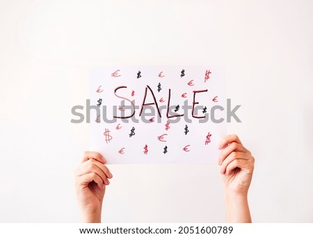Hands hold a poster with the word SALE on white background. Sale concept.