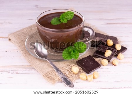 
Cup of hot chocolate with hazelnuts on a white wooden background