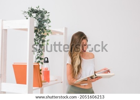 Young woman looking photo album at home. Memories and leisure concept.