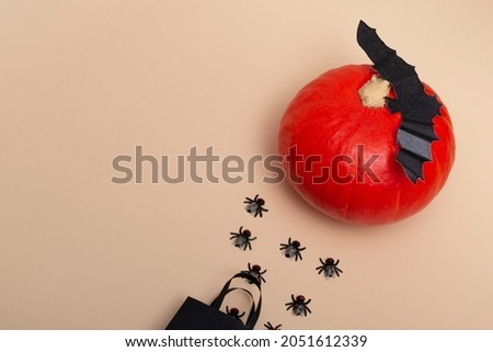Top view on a beige background black package with flies, pumpkin and bats. Close up of a halloween party. invitation layout. Banner