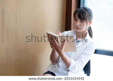 Portrait of young beautiful asian student reading a book sitting in library with copy space.