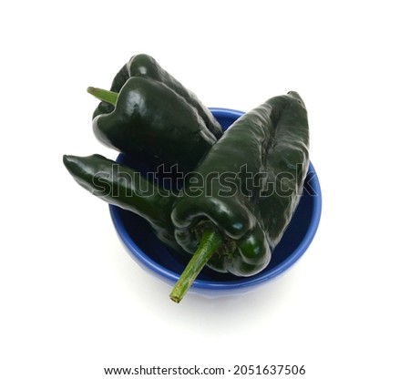 Stack dark green poblano peppers isolated in bowl on white 