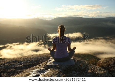 Back view of a yogi doing yoga in the mountain at sunrise Royalty-Free Stock Photo #2051672411