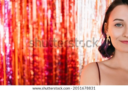 Christmas party. Festive woman. Stylish look. Pretty smiling lady purple curly hair posing on shimmering golden red cascade curtain decoration background copy space blur light.