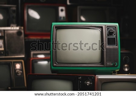 Green retro old television with blank screen in the room, many old TVs background. Vintage style filtered photo Royalty-Free Stock Photo #2051741201