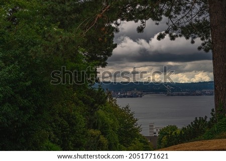 SMITH COVE SEATTLE FRAMED WITH TREES FROM MAGNOLIA WITH DARK CLOUDS 