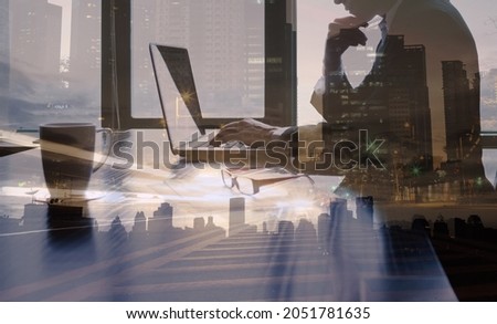 Double exposure silhouette of successful businessman is working at office desk. Thoughtful entrepreneur using laptop computer in a modern futuristic setting. 
 Royalty-Free Stock Photo #2051781635