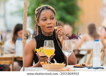 Smiling latina woman enjoying fast food and drinks at an outdoors terrace