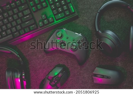 gamer work space concept, top view a gaming gear, mouse, keyboard, joystick, headset with rgb color on black table background.