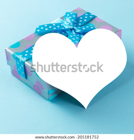 Blue gift box with heart shaped plain card over blue background