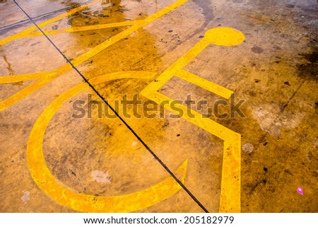 Handicapped yellow symbol on asphalt.