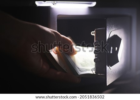 Steel safe with money. Hand putting password in the safety money box in hotel room