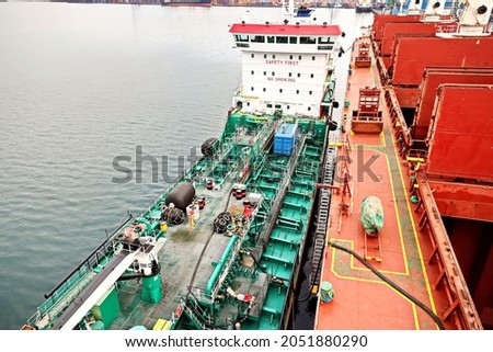 Bunkering operations at the port. Bunker barge alongside of the vessel. Port of Vostochnyy. Russia, December, 2020. Royalty-Free Stock Photo #2051880290