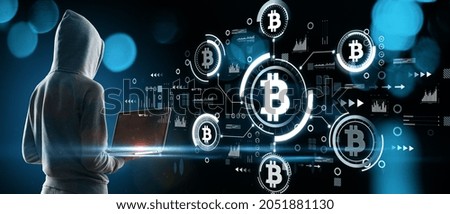 Young hacker using laptop with abstract bitcoin hologram on blurry blue bokeh background. Cryptocurrency, finance and blockchain concept. Double exposure Royalty-Free Stock Photo #2051881130