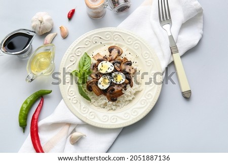 Plate of delicious rice with mushrooms on light background