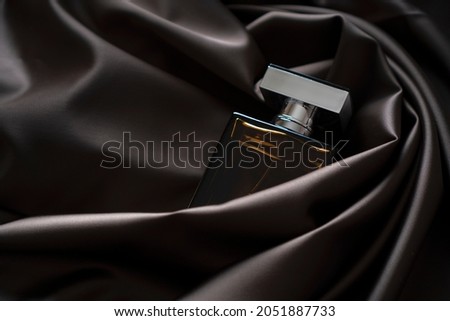 Men's perfume bottle in satin cloth waves draperies. Royalty-Free Stock Photo #2051887733