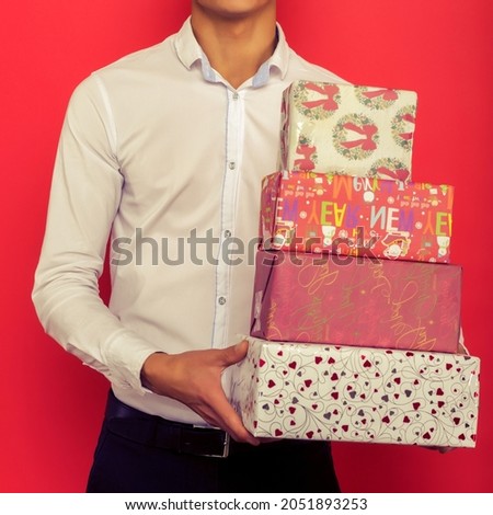 Handsome asian businessman holding gift box over red background - image