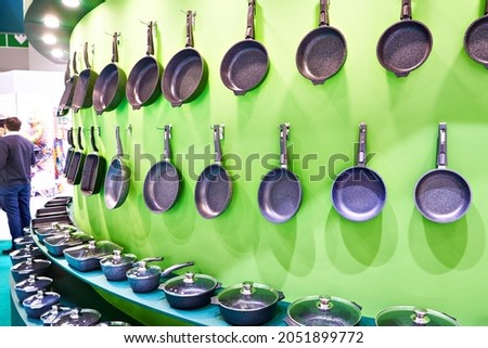 Kitchenware frying pans on the wall in household goods store