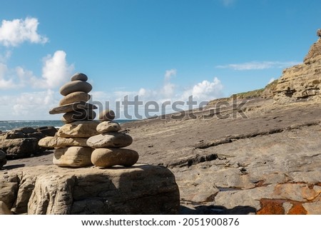 Pile of rocks stack on each over in nature environment. Warm sunny day, cloudy sky. Balance, patience and zen concept