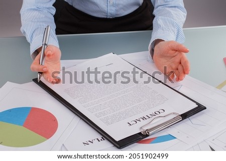 Close up business woman reading a contract at table in office.