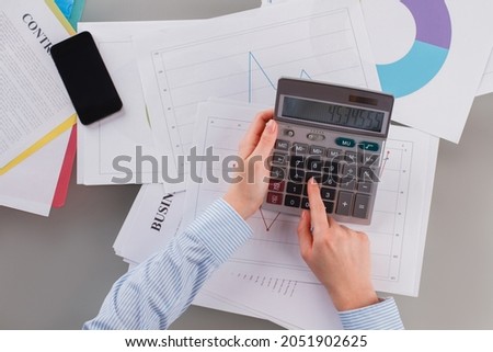 Young businesswoman working with calculator and business documents in office.