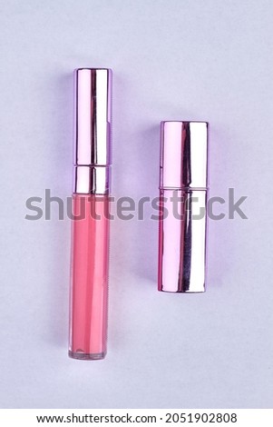 Top view of pink lipstick and lip gloss on white background.
