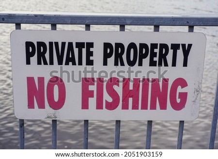 No Fishing sign on steel fence beside river. 