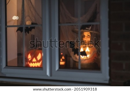 Woman witch carrying a pumpkin for Halloween night - Spooky scene with halloween symbols and signs  - holidays, culture and lifestyle in UK and United States