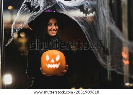 Woman witch carrying a pumpkin for Halloween night - Spooky scene with halloween symbols and signs  - holidays, culture and lifestyle in UK and United States